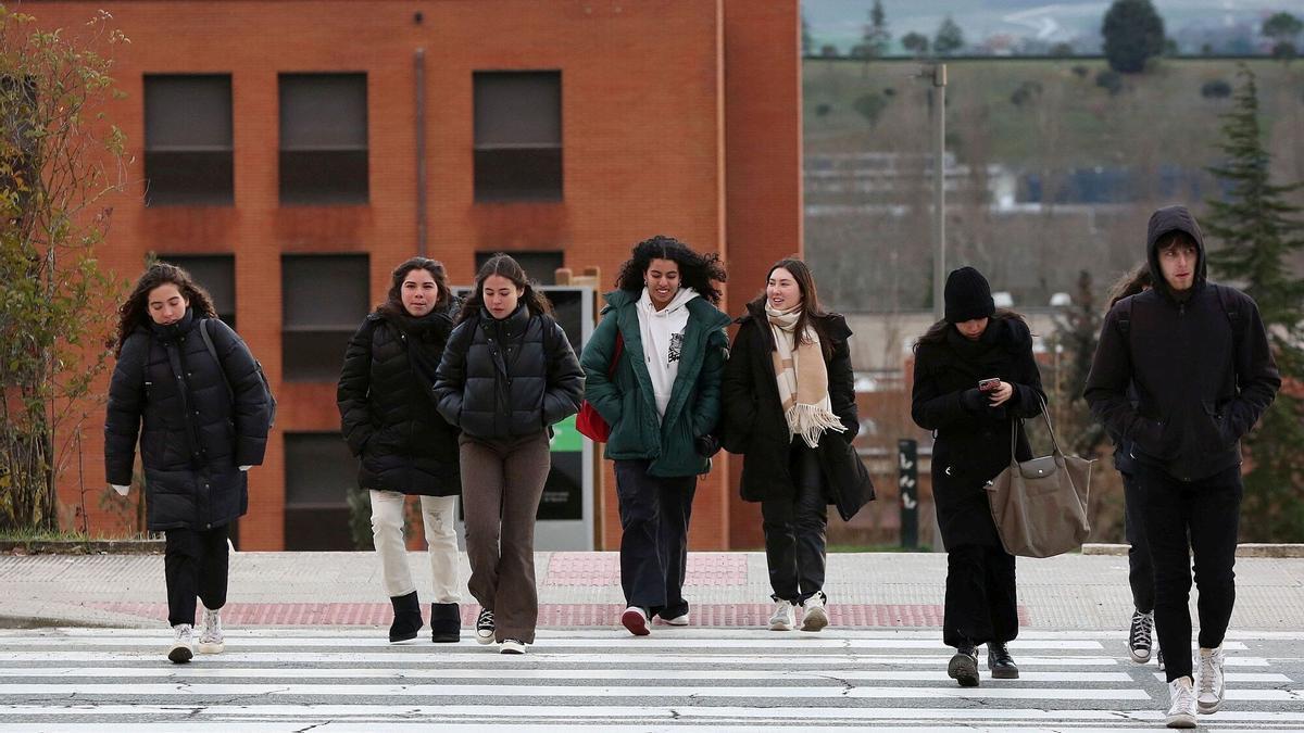 Varios jóvenes se protegen del frío en Pamplona.