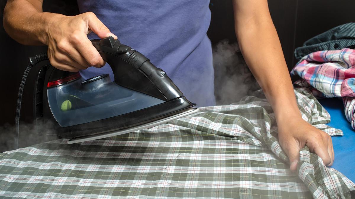 Una persona plancha una camisa.