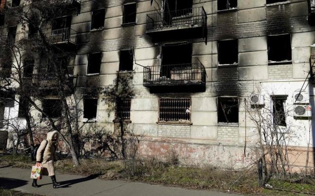 Una mujer pasea ante un edificio bombardeado en Lugansk. Una mujer pasea ante un edificio bombardeado en Lugansk.