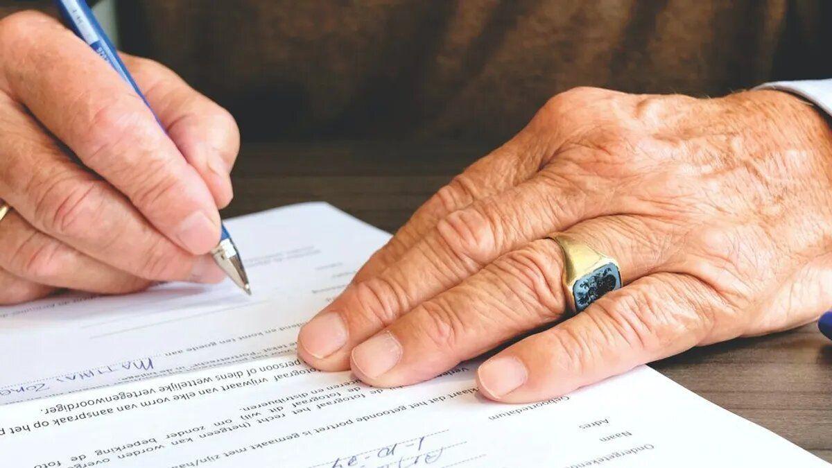 Un hombre avala con su firma un documento testamentario.