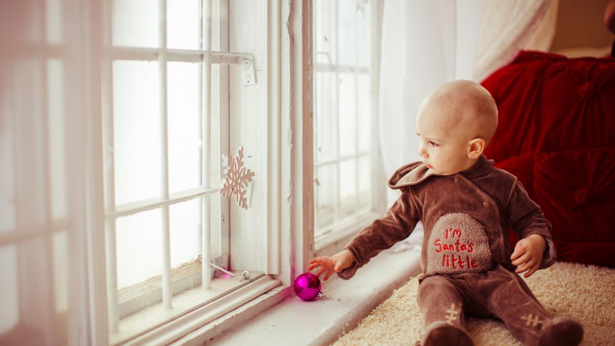 Un niño, abrigado con ropa de invierno y encima de una alfombra.