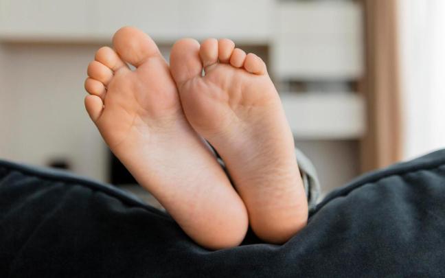 Pies apoyados en el respaldo de un sofá.