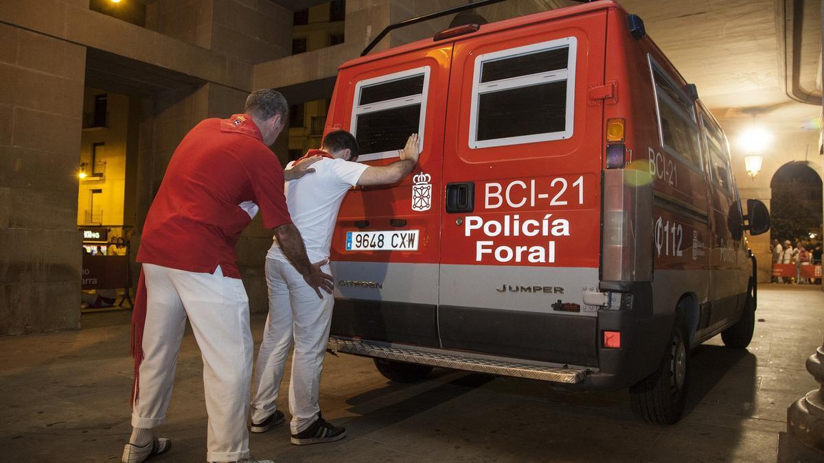 Un Policía Foral de paisano cachea a un sospechoso de robo en fiestas de San Fermín.