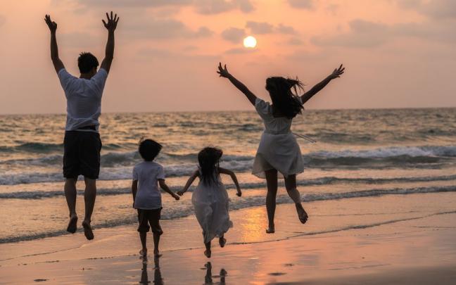 Una familia disfrutando del atardecer en la playa.