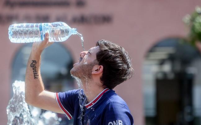 Un joven se echa agua para combatir el calor