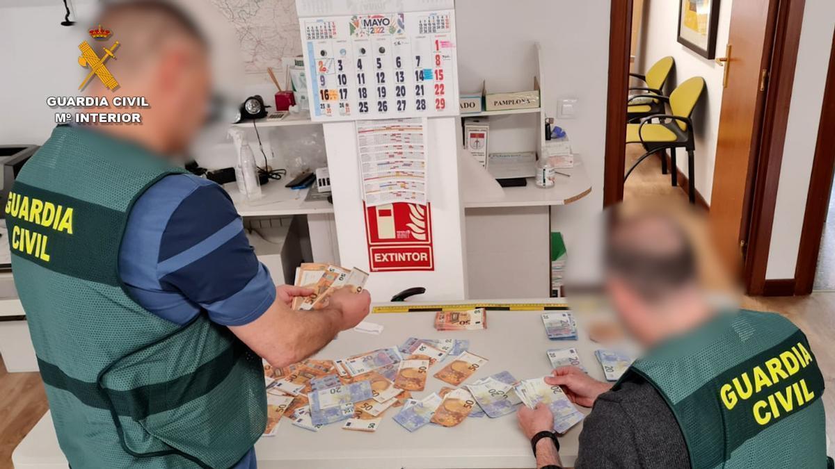 Imagen de dos agentes de la Guardia Civil con el dinero incautado