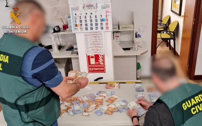 Imagen de dos agentes de la Guardia Civil con el dinero incautado