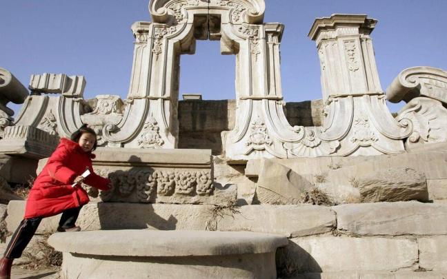Un visitante camina por las ruinas del Palacio Antiguo de verano, antiguos jardines imperiales de la dinast&iacute;a Qing