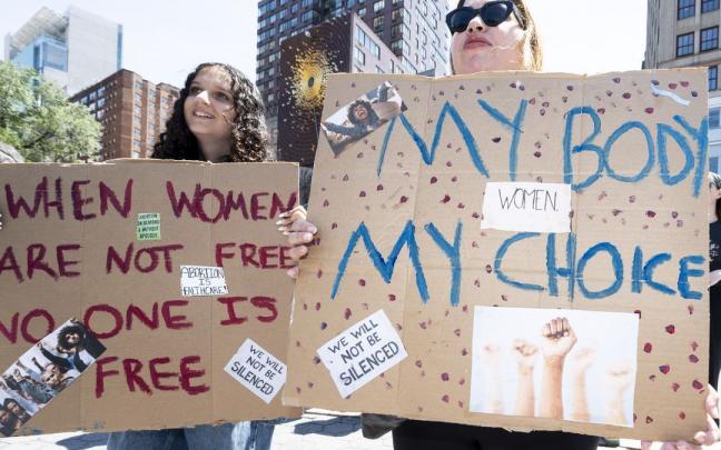 Dos mujeres sostienen pancartas durante una manifestación por el derecho al aborto.