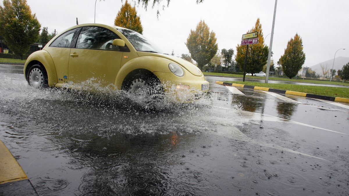 Un coche circula sobre una balsa de agua provocada por fuertes lluvias en Pamplona.