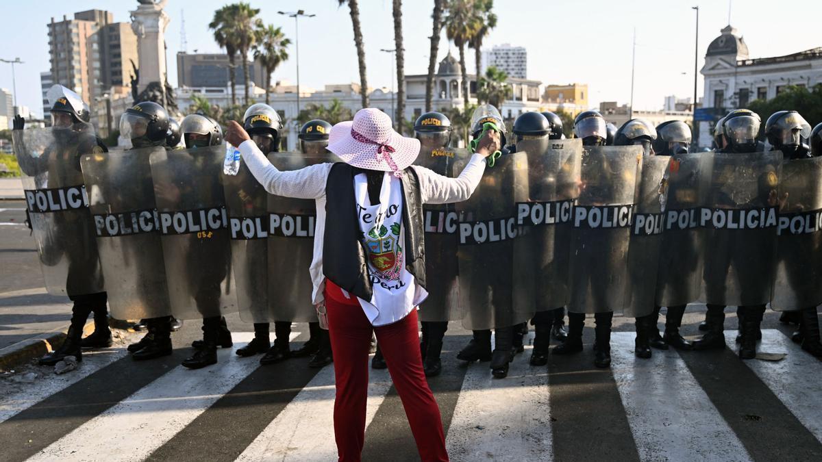 Una mujer hace frente a un grupo de policías en Lima.