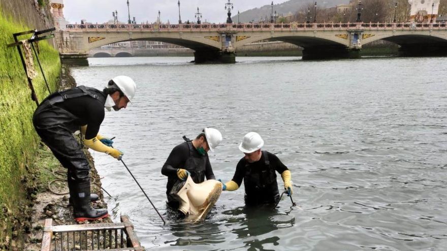 Un grupo de operarios retira un inodoro del cauce del Urumea en Donostia