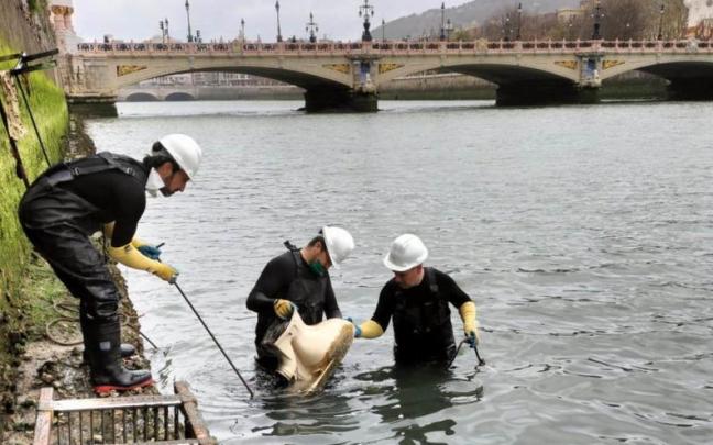 Un grupo de operarios retira un inodoro del cauce del Urumea en Donostia
