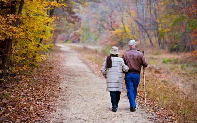 Una pareja de ancianos disfrutan de un paseo durante el otoño Una pareja de ancianos disfrutan de un paseo durante el otoño