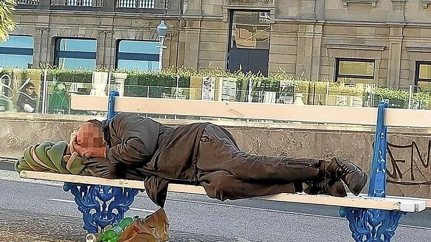 Un hombre sin hogar duerme tendido sobre un banco de la calle Reina Regente de Donostia.