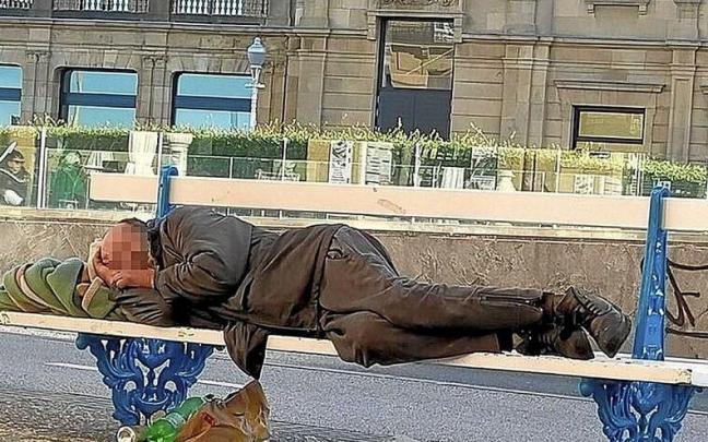 Un hombre sin hogar duerme tendido sobre un banco de la calle Reina Regente de Donostia.
