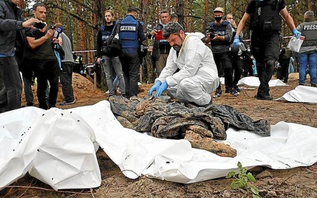 Un forense examina uno de los cuerpos hallados en una fosa com&uacute;n en la localidad de Izium.