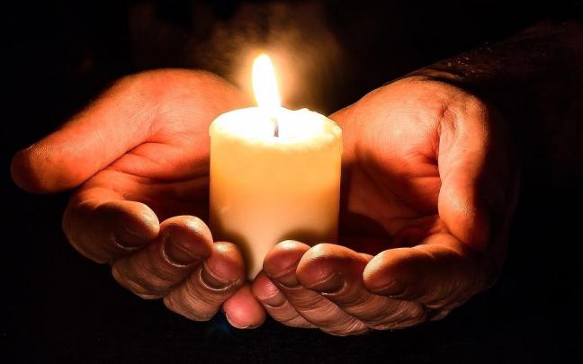 Una persona sostiene una vela entre las manos Una persona sostiene una vela entre las manos