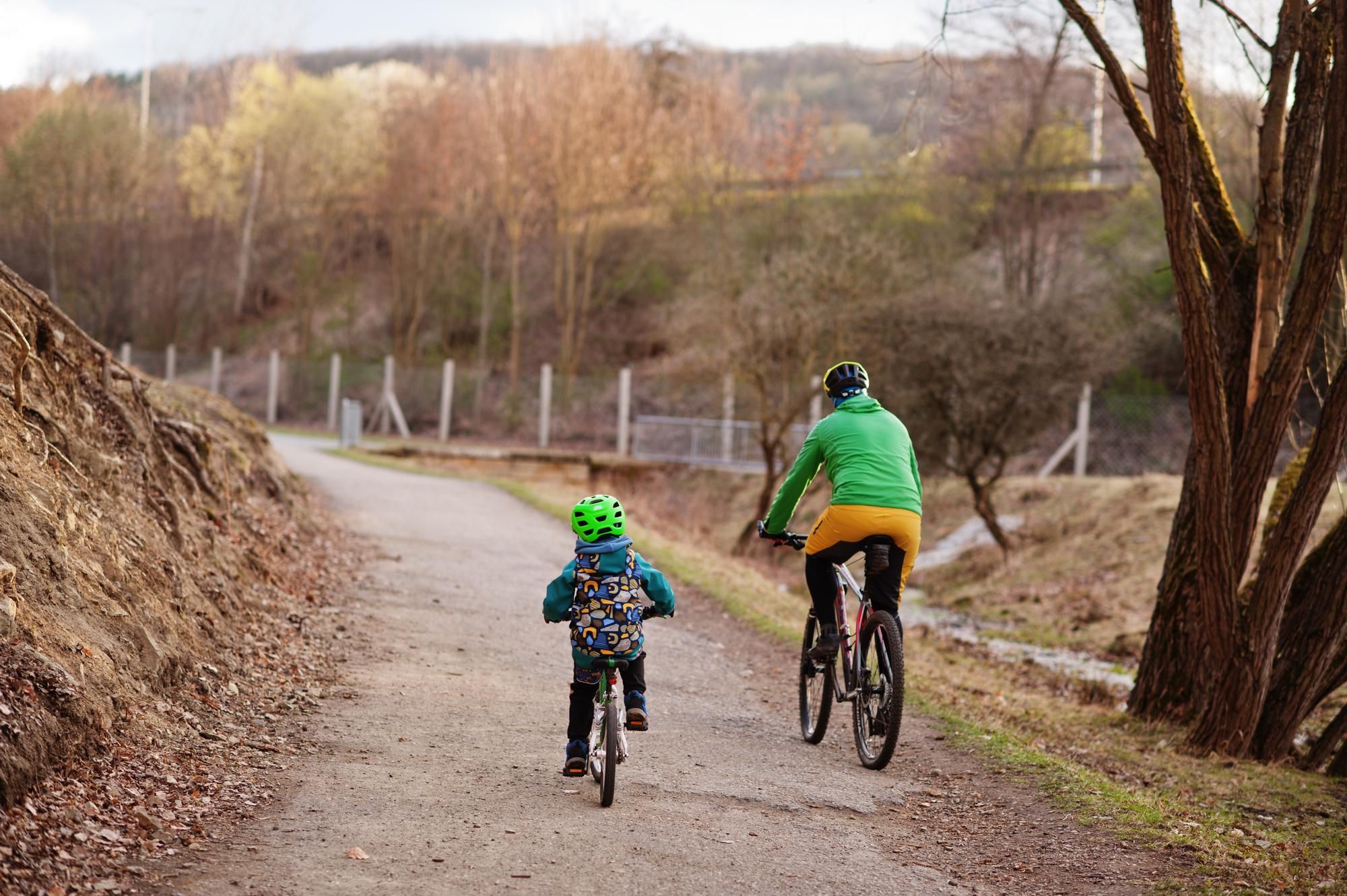 Un niño y un adulto dan un paseo en bici por el campo.