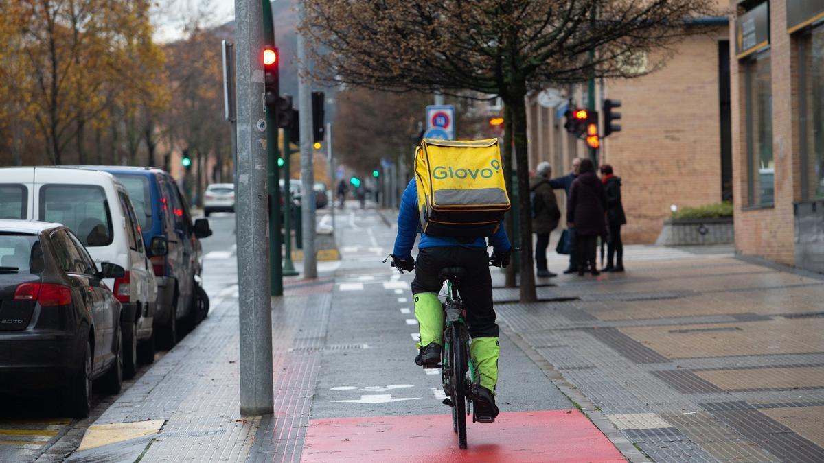 Un trabajador de envío de pedidos a domicilio (Glovo) circulando con su bicicleta por el carril bici de la Rochapea.