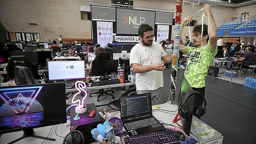 Julen Ortega (i) y Ellande Pérez colocan una tira led alrededor de una torre hecha con latas de refresco.