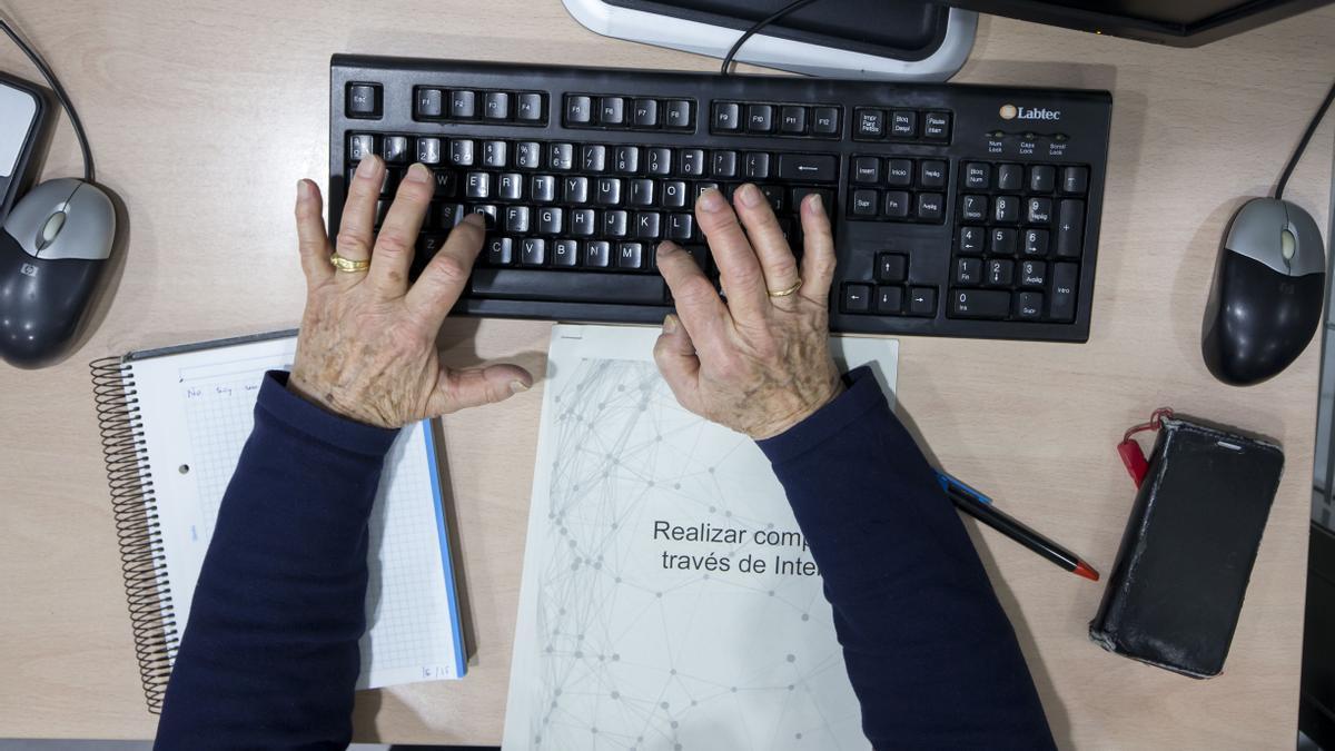 Un hombre anciano realiza uno de los talleres para paliar la brecha digital.