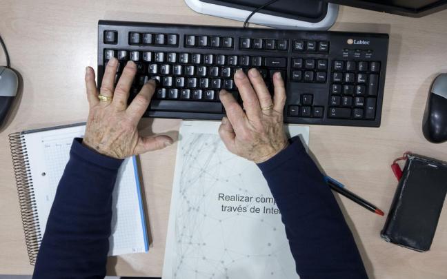 Un hombre anciano realiza uno de los talleres para paliar la brecha digital.