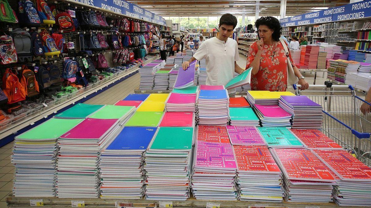 Un joven y su madre, eligiendo cuadernos en un puesto de venta de material escolar para la vuelta a clase.