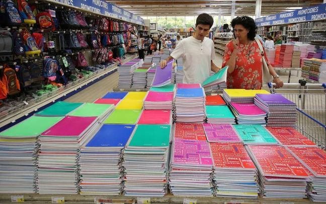 Un joven y su madre, eligiendo cuadernos en un puesto de venta de material escolar para la vuelta a clase.