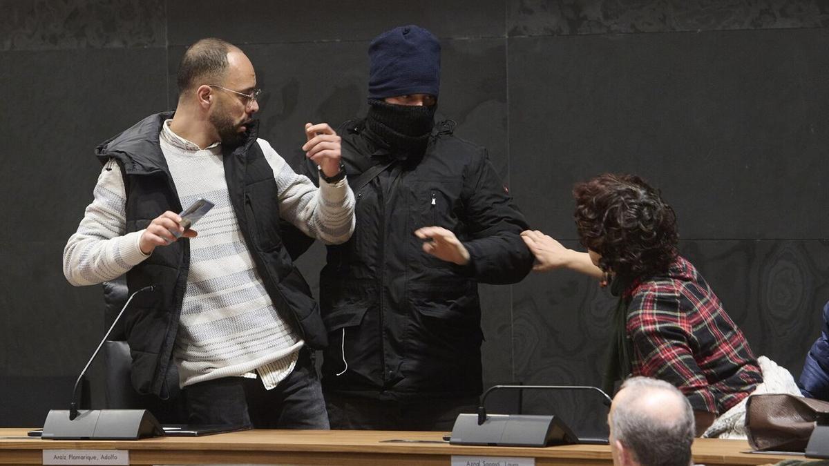 Momento de la performance en la que un encapuchado 'detiene' a un hombre en el Parlamento foral.