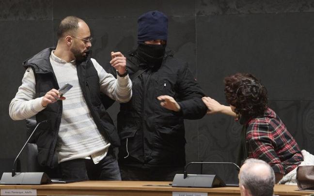 Momento de la performance en la que un encapuchado 'detiene' a un hombre en el Parlamento foral. Momento de la performance en la que un encapuchado 'detiene' a un hombre en el Parlamento foral.