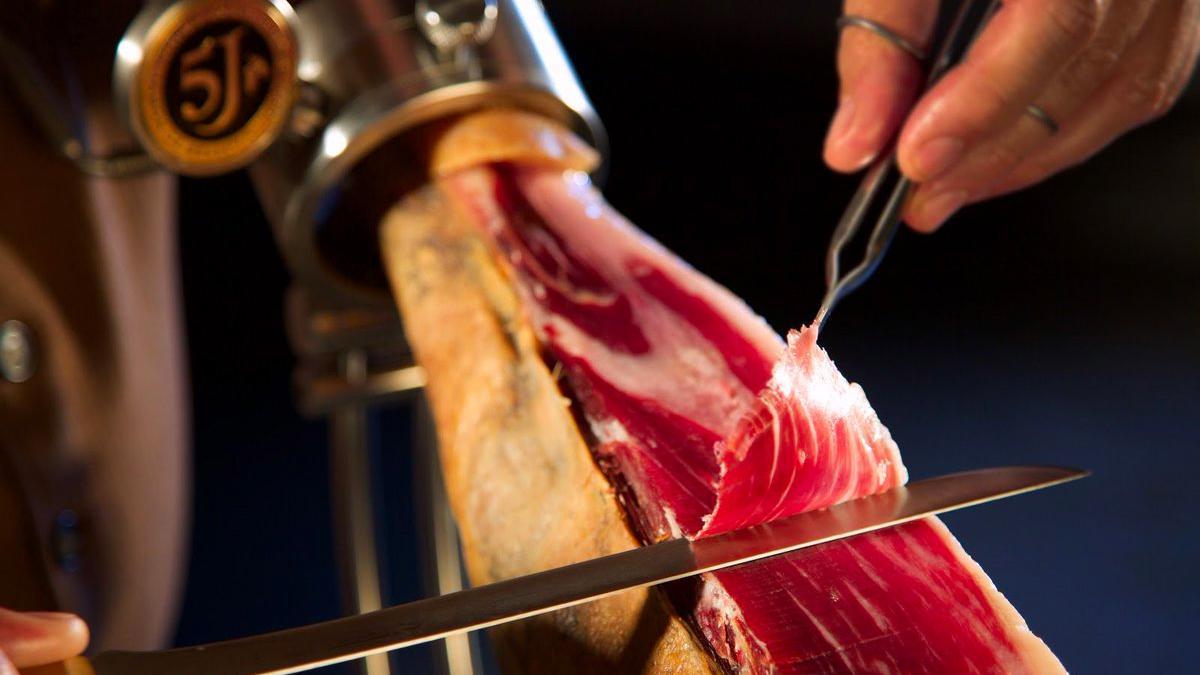 Una persona corta un jamón Ibérico Cinco Jotas como el que se sorteará en Mutriku