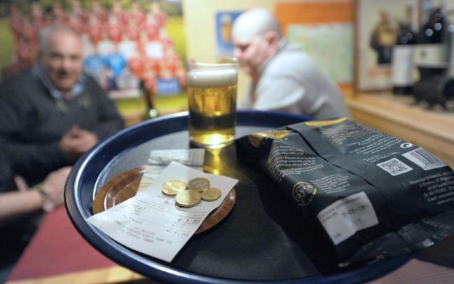 Un camarero entrega el tique con las vueltas y la consumición en un bar.