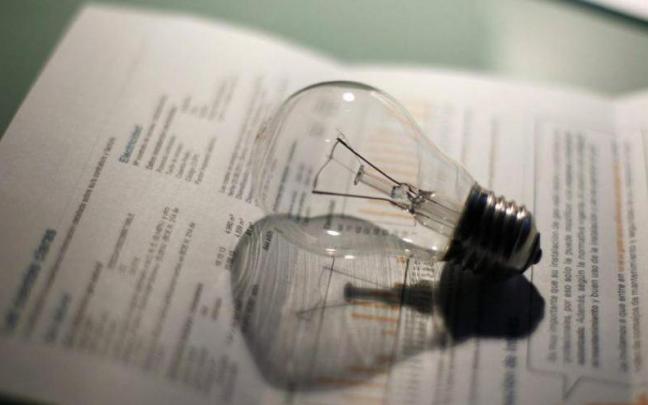 Una bombilla junto a la factura de la luz.