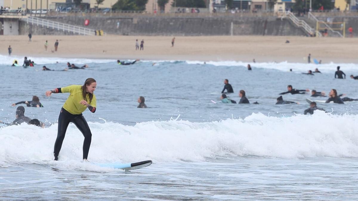 Una alumna de los cursillos de otoño surfea una ola en la playa de la Zurriola.