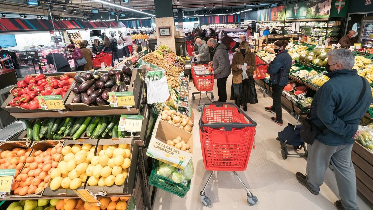 Varias personas hacen la compra en un supermercado.