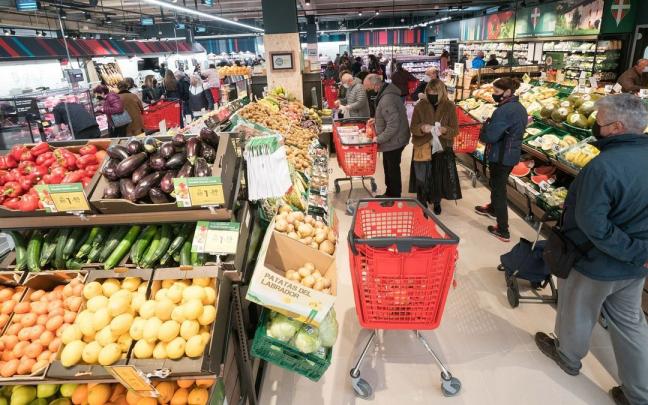 Varias personas hacen la compra en un supermercado.