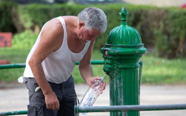 Un hombre llena una botella de agua en una de las fuentes de Pamplona