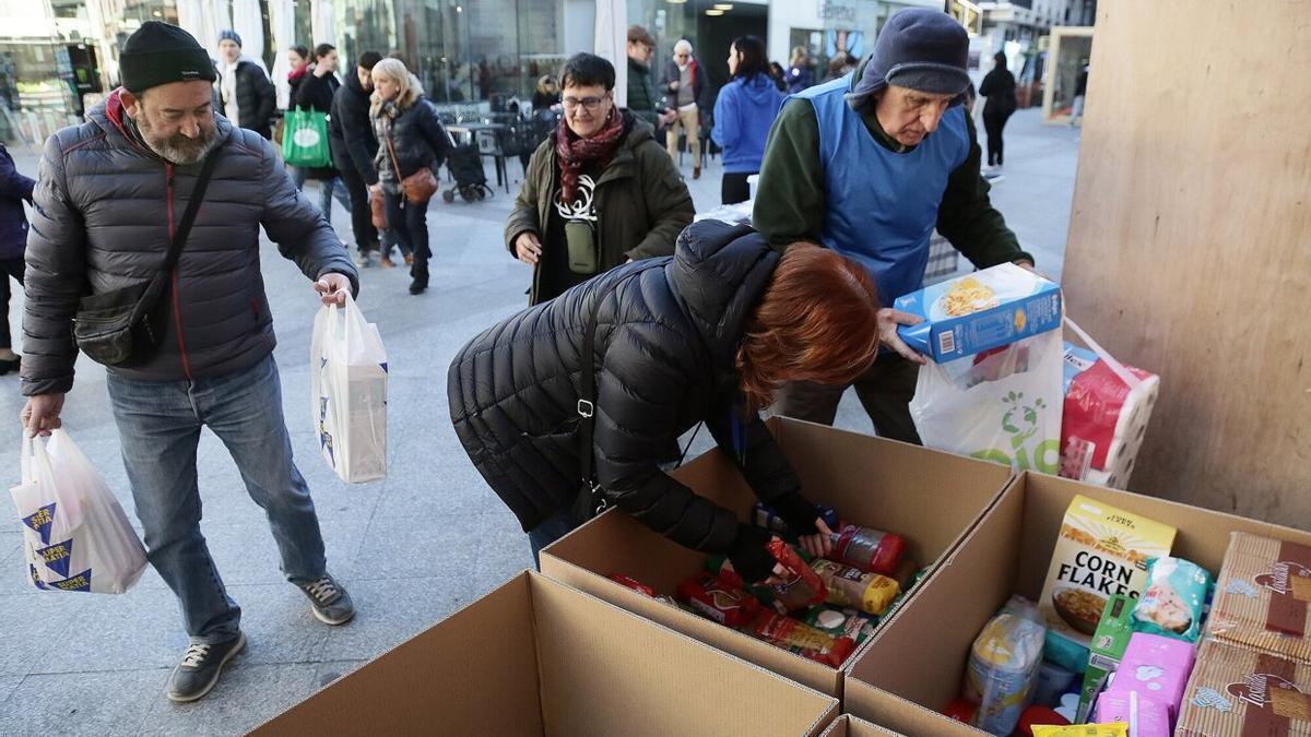 Varios voluntarios de Zaporeak ordenan en cajas la comida que está donando la gente en el puesto de La Bretxa.