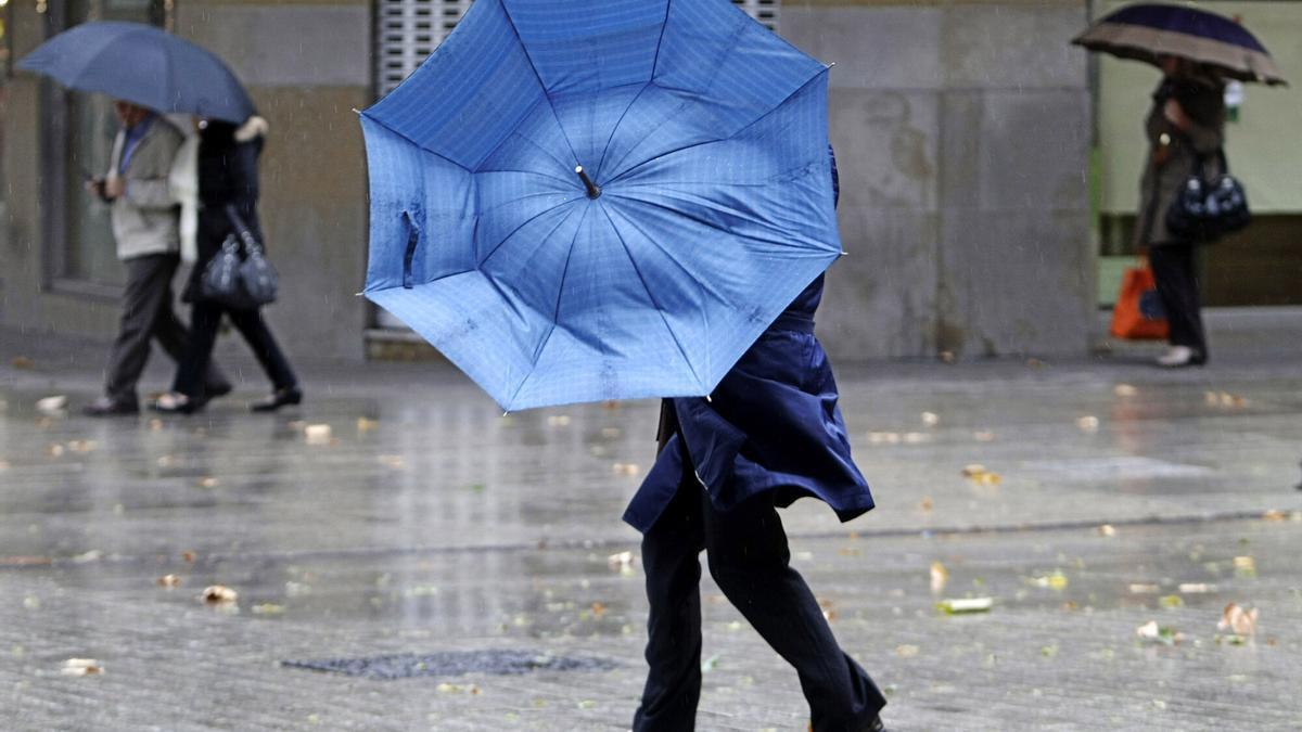 Una mujer, con problemas con su paraguas a causa del viento en Pamplona.