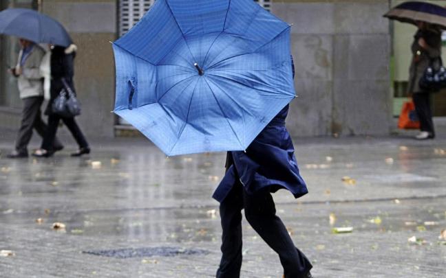 Una mujer, con problemas con su paraguas a causa del viento en Pamplona.