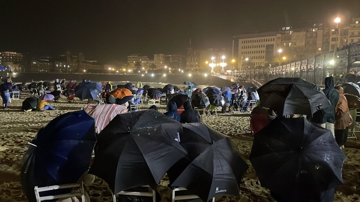 Decenas de personas se cobijan bajo paraguas esperando a los fuegos británicos que finalmente fueron suspendidos