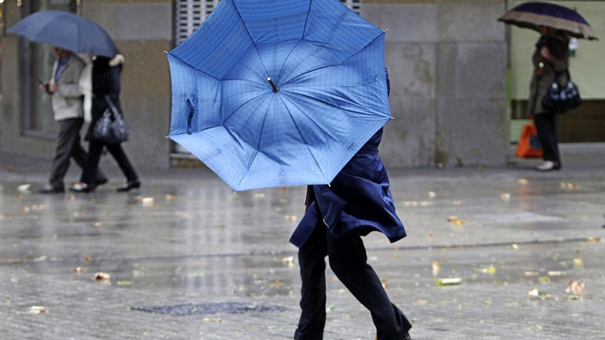 Una mujer, con problemas con su paraguas a causa del viento en Pamplona