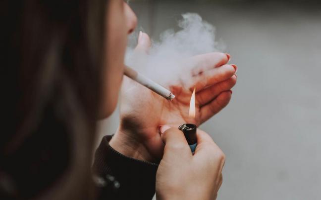 Una mujer enciende un cigarrillo.