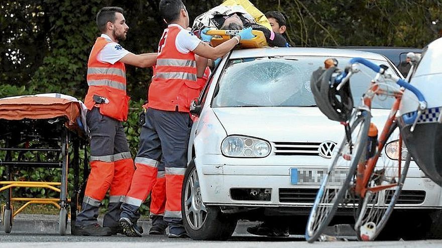 Los sanitarios bajan del techo del coche al ciclista.