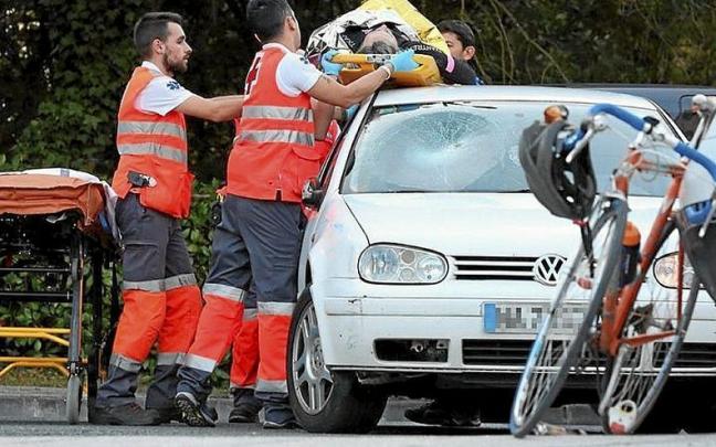 Los sanitarios bajan del techo del coche al ciclista.