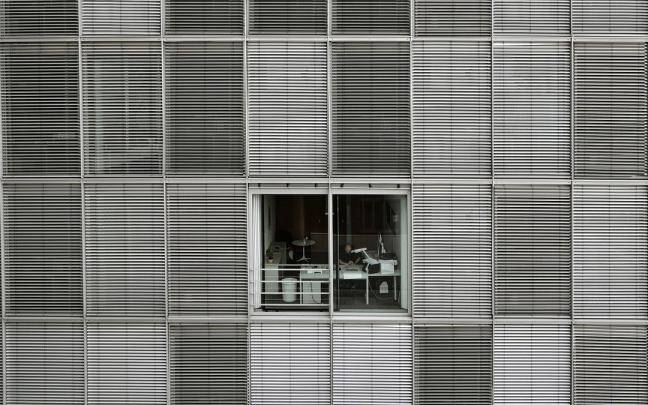 Un hombre trabajando en un despacho con las persianas levantadas. Un hombre trabajando en un despacho con las persianas levantadas.