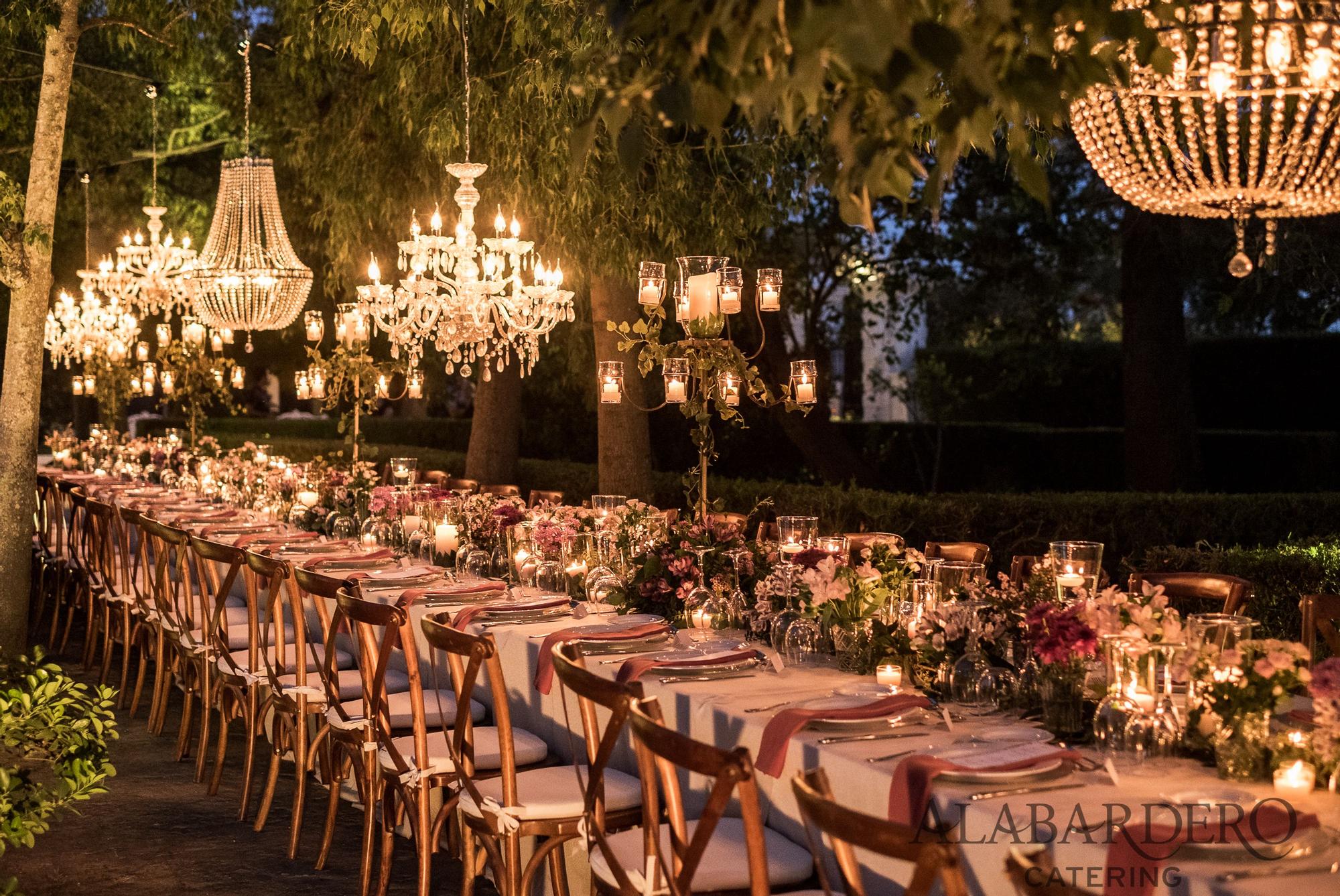 Mesa decorada con muchas flores y grandes lámparas.