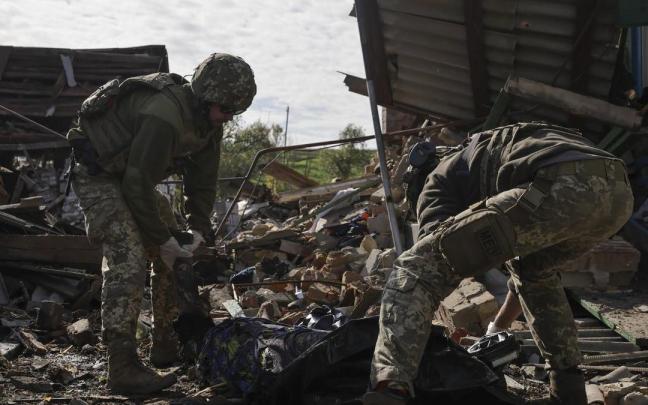 Dos soldados ucranianos retiran el cadáver de un civil muerto en los bombardeos rusos.