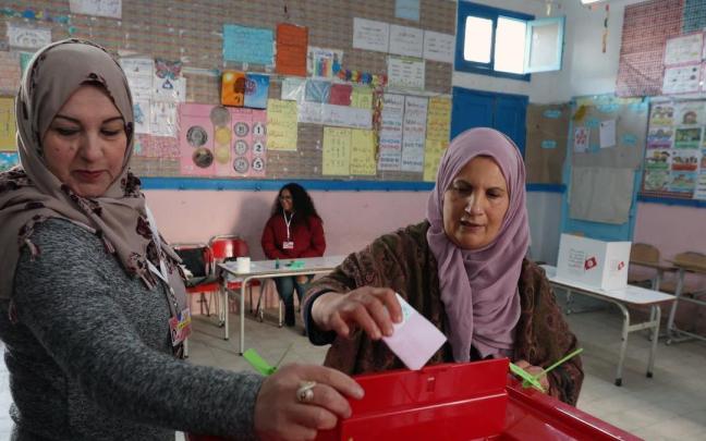 Una mujer deposita su voto en un colegio electoral de T&uacute;nez.